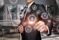 A man in a suit holds up a magnifying glass to a graphic of justice scales