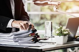 A businessman flicks through a pile of documents on his desk