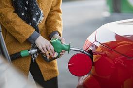 A woman fills up her car at a petrol station
