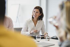 A business woman laughs with colleagues in a meeting