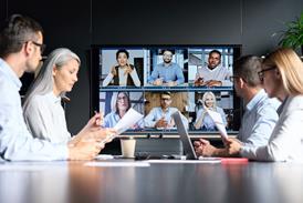 A group of four colleagues sit round a table while listening to clients on a virtual call