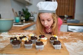 A young girl admires freshly baked cupcakes