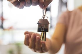 A woman holds out her hand to receive a set of keys to a new house