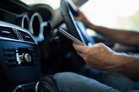 A man checks his phone while driving