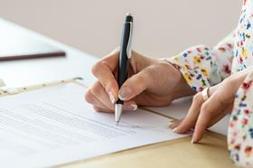An anonymous woman signs a document