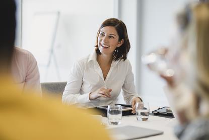 A business woman laughs with colleagues in a meeting