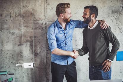 Two male work colleagues greet each other