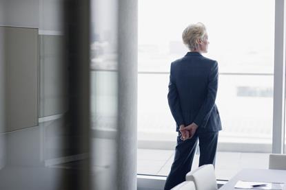 An older businesswoman looks out of an office window