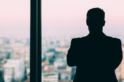 Male office worker looks out of a window