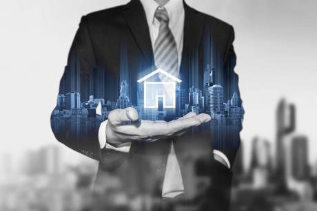 An anonymous businessman holds an image of a digital house in his hand