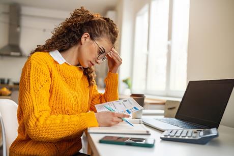 A young woman looks at bills at home