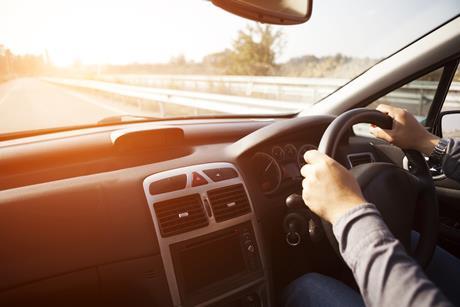 Close up shot of car dashboard with driver behind the wheel