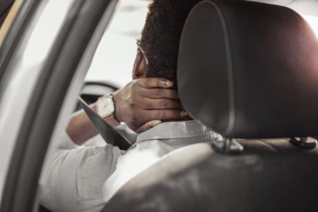 A driver holds his neck in pain