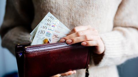 A woman takes £10 notes out of a purse