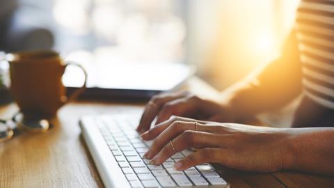 An anonymous woman typing on a computer keyboard