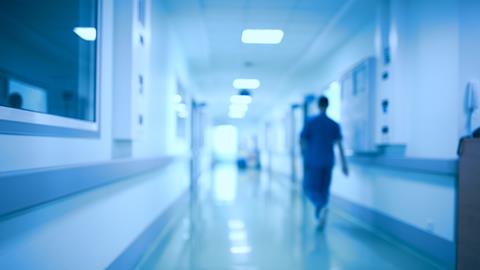 A blurred image of a doctor walking down a hospital corridor