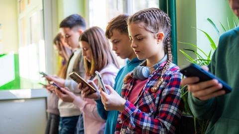 A group of children scroll on their phones