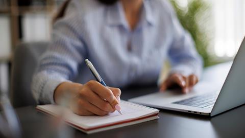 A journalist takes notes during a remote hearing