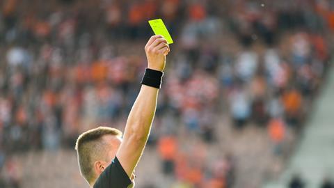 Football referree holds up yellow card