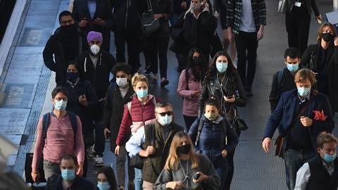 Commuters wearing masks walk through London train station