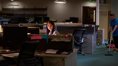 A young woman works late at night in the office