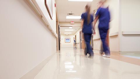 Blurred image of medical staff walking down hospital corridor