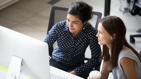 Two female colleagues work together at a computer