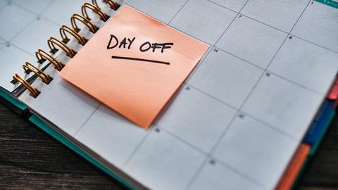 Post-it note with 'Day off' written on it is stuck to an open page of a diary