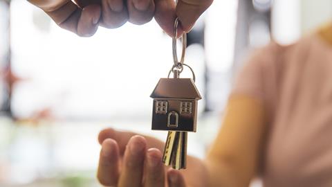 A woman holds out her hand to receive a set of keys to a new house