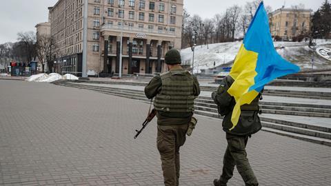 Ukrainian soldiers walk with the Ukrainian national flag in downtown Kyiv