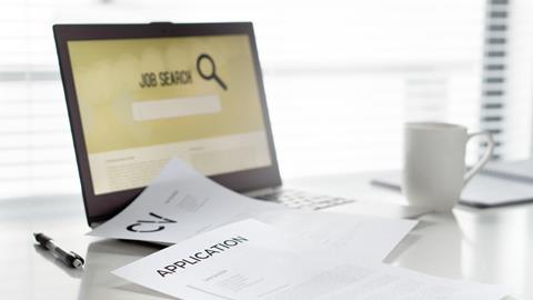 A CV and job application on a desk with a laptop displaying a job search