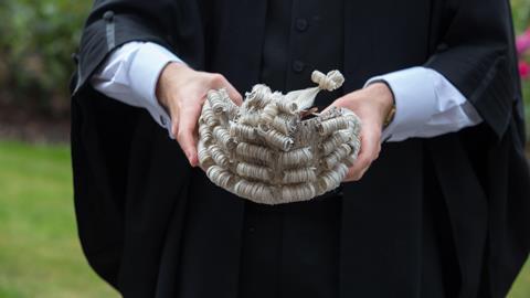 A barrister holds a wig ready to wear