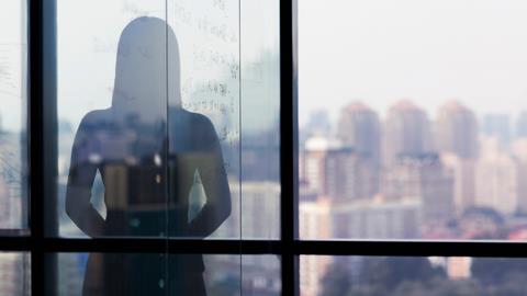 A silhouette of a woman against the backdrop of a window overlooking a city skyline