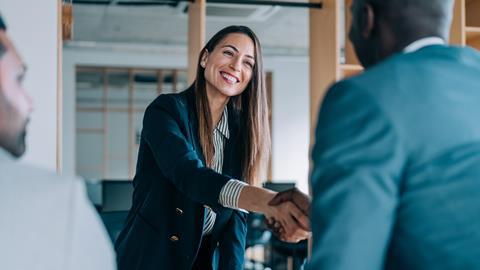 A woman smiles as she shakes hands with her client