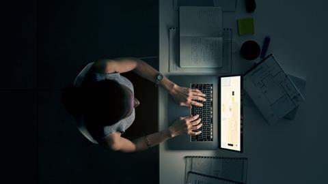 Woman sat at laptop working late at night