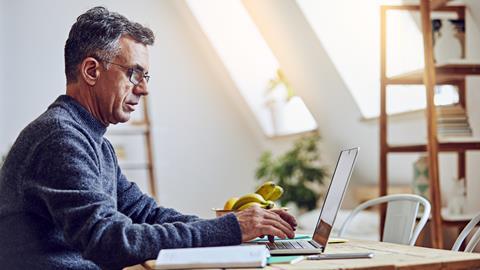 A man types on a laptop at home