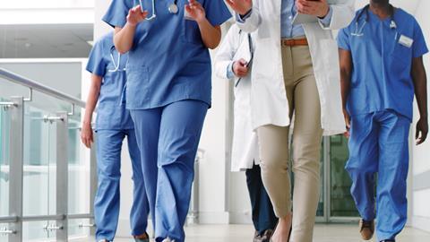 A group of doctors walk down a hospital corridor