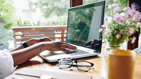 Woman types on laptop at kitchen table