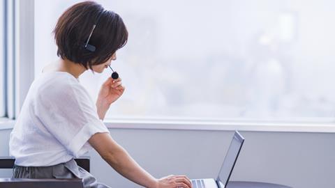 An woman talks into a headset as she takes part in a video call