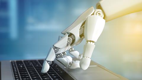 Robot hand typing on laptop