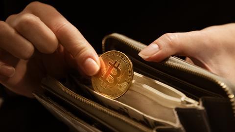 A person takes a Bitcoin 'coin' out of a wallet