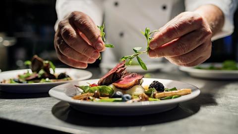 A chef places the finishing touches to a plate of food in a restaurant kitchen