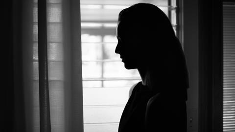 Silhouette of a woman's side profile against light from a window