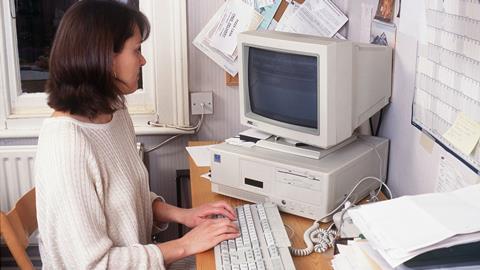 A female office worker sits at a desk and types on her computer keyboard, 1996