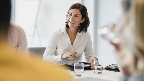 A business woman laughs with colleagues in a meeting