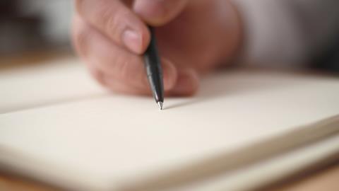 A close up of a man's hand holding a pen to paper