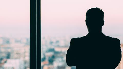 Male office worker looks out of a window