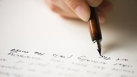 A close up of a hand writing on a piece of paper with a fountain pen