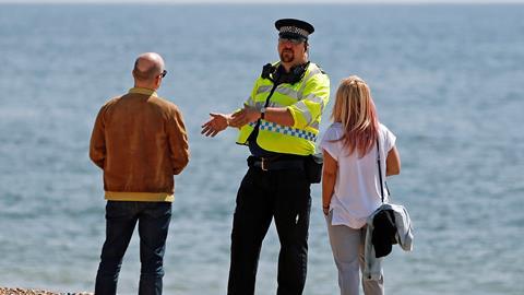 Police officer talks to a man and woman on Brighton beac
