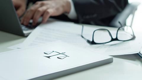 Justice scales on a file next to a laptop